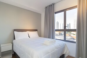 Une chambre d’hôtel avec un lit, une table de chevet et une fenêtre avec des rideaux.