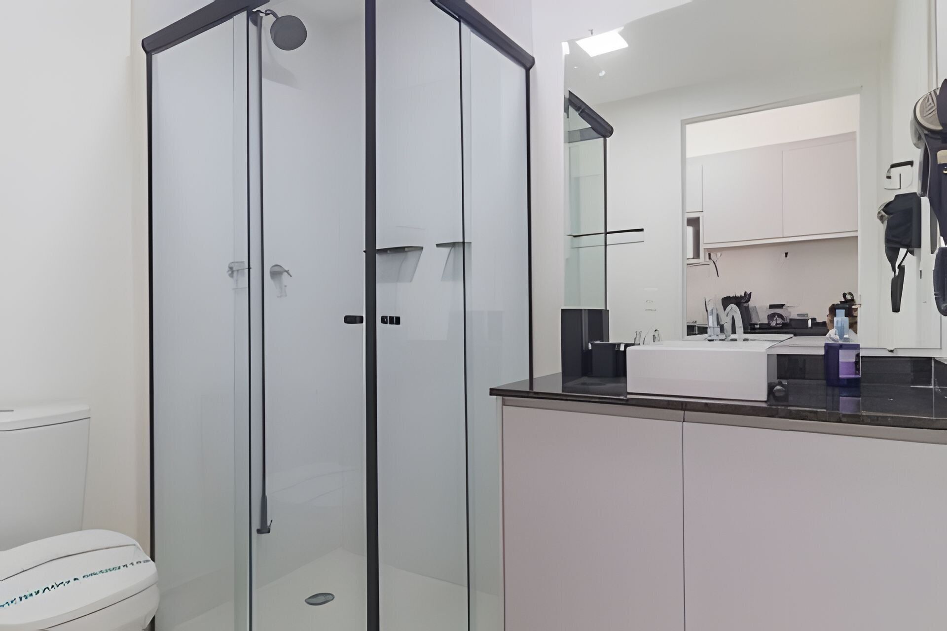 Une salle de bain moderne avec une douche à parois de verre, un lavabo blanc et un grand miroir.