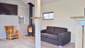 A cozy living room with a wood-burning stove, a brown armchair, and a gray sofa. - Lovely home in Flekkefjord with sauna (Flekkefjord)