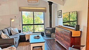 A cozy living room with a sofa, a coffee table, a fireplace, and a TV. - Infinity at Surf Beach (Surf Beach)