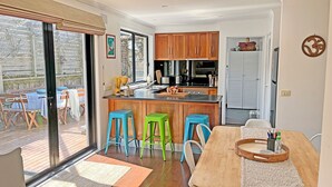 A modern kitchen with wooden cabinets, a central island, and colorful stools. - Infinity at Surf Beach (Surf Beach)