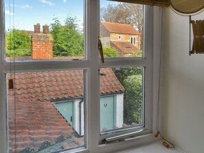 Una ventana con vistas a una casa de ladrillo y un edificio verde con tejado inclinado.