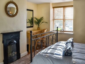 Un dormitorio con cama, cómoda y chimenea.