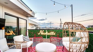 An outdoor seating area with wicker furniture and a neon sign reading "Nashville". - Modern Bachelorette Retreat — Rooftop, Karaoke, Near Downtown Broadway. (Nashville)