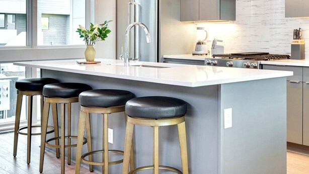 A modern kitchen with a large island, bar stools, stainless steel appliances, and a view of the city. - Modern Bachelorette Retreat — Rooftop, Karaoke, Near Downtown Broadway. (Nashville)