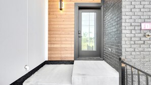 A modern entrance with a wooden wall, a black door, and a concrete step leading to a balcony. - Modern Bachelorette Retreat — Rooftop, Karaoke, Near Downtown Broadway. (Nashville)