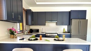 Una cocina moderna con armarios oscuros, una isla central, una estufa y un refrigerador.
