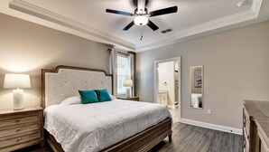 A bedroom with a bed, nightstands, a ceiling fan, and a mirror.