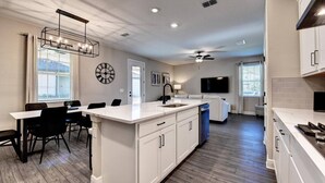 A modern kitchen with a central island, dining area, and a ceiling fan.