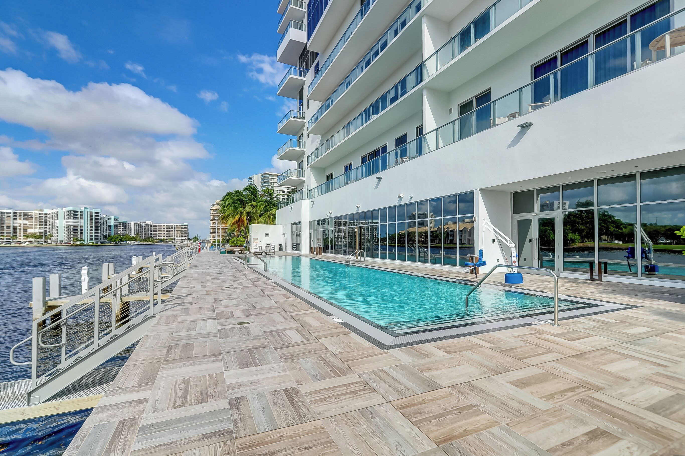 Un hotel moderno con piscina, vista al agua y un amplio espacio exterior con terraza de baldosas.