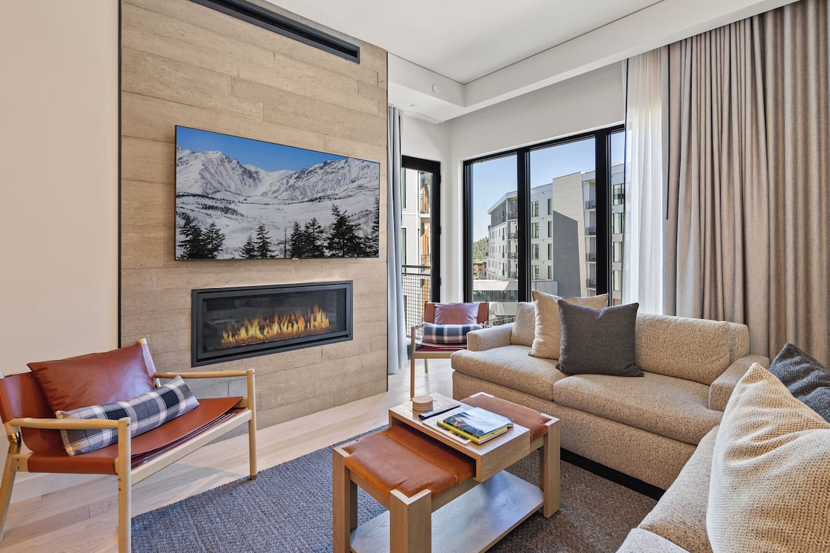 A modern living room with a fireplace, a sofa, a chair, and a coffee table.
