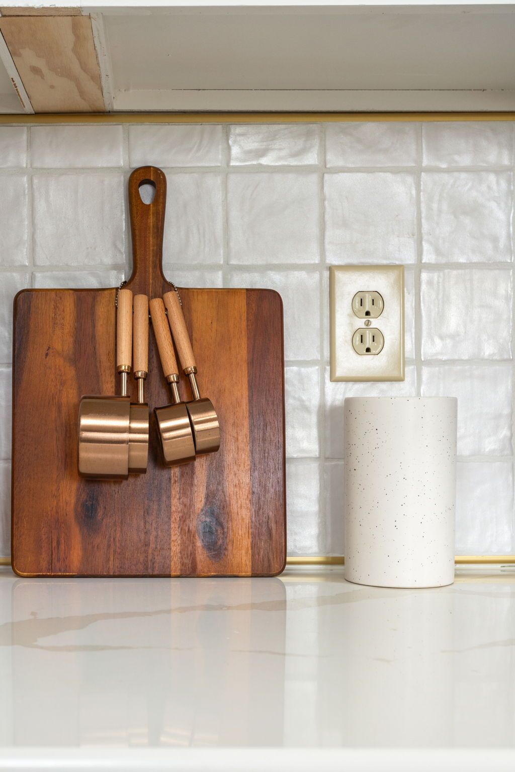 Une planche à découper en bois, accompagnée d’un ensemble de couteaux et d’une tasse blanche, posée sur un plan de travail de cuisine.