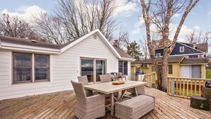 Une terrasse avec une table et des chaises, une maison en arrière-plan et des arbres sans feuilles.