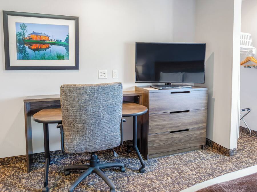 Une chambre d’hôtel équipée d’un bureau, d’une chaise, d’une télévision et d’un tableau encadré au mur.