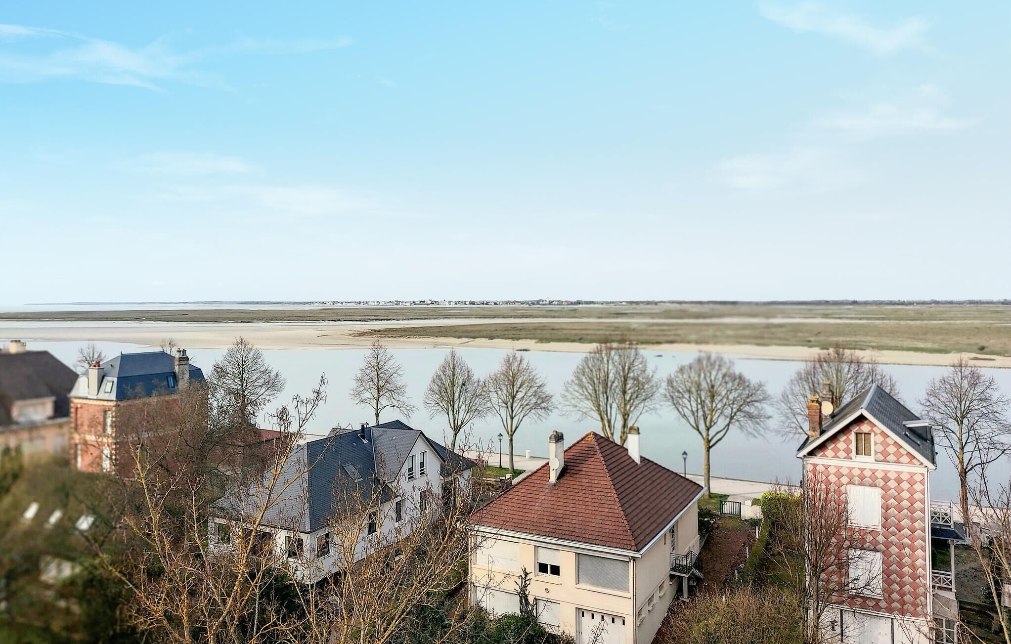 A residential area with houses, a river, and a distant shoreline.