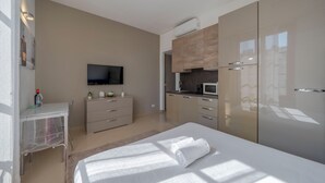 A modern hotel room with a bed, a desk, a TV, a kitchenette, and a large wardrobe. - Milano Apartments Alzaia 54 (Milan)