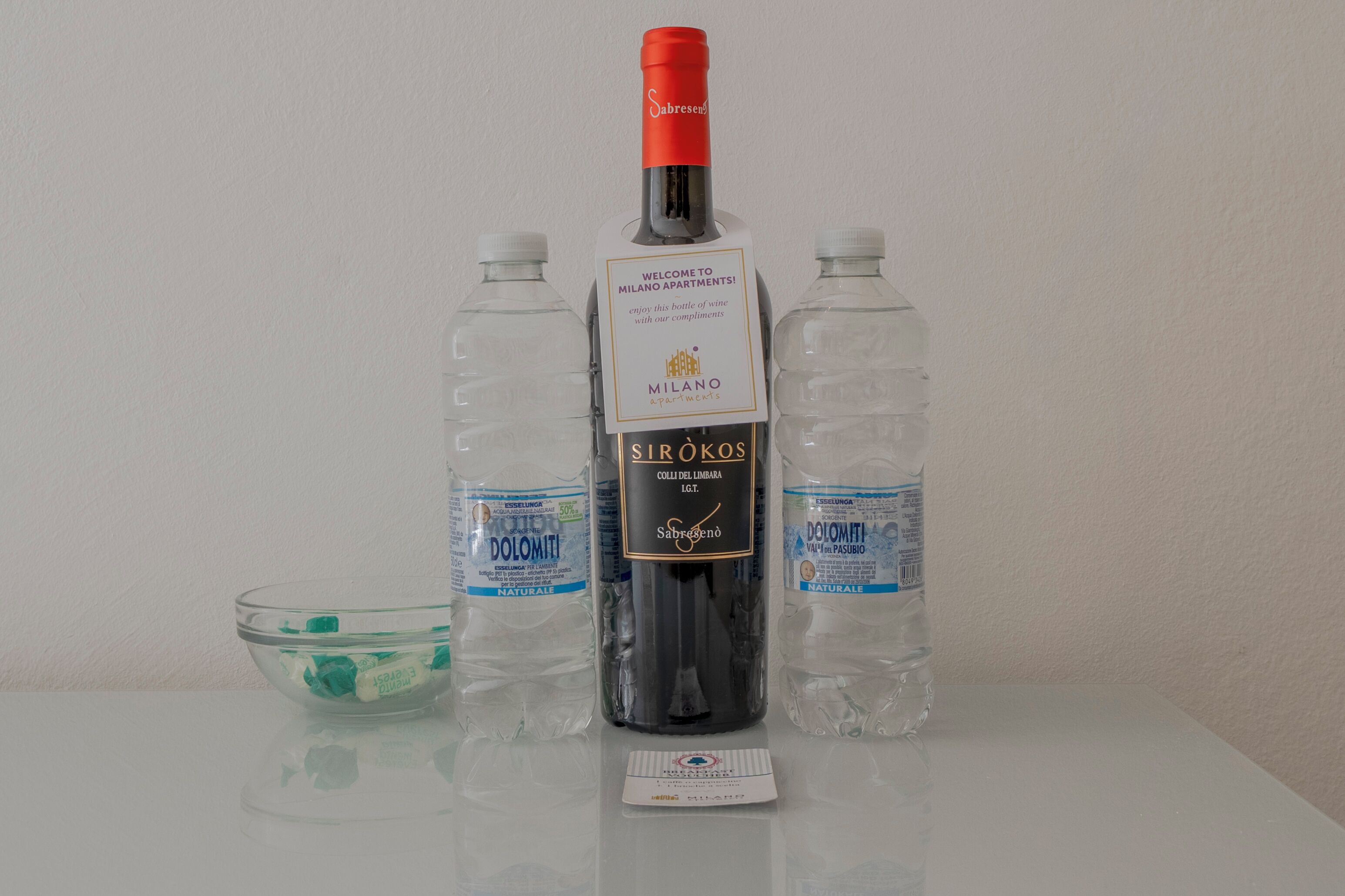 Une bouteille de vin, deux bouteilles d’eau et un saladier en verre sur une table.