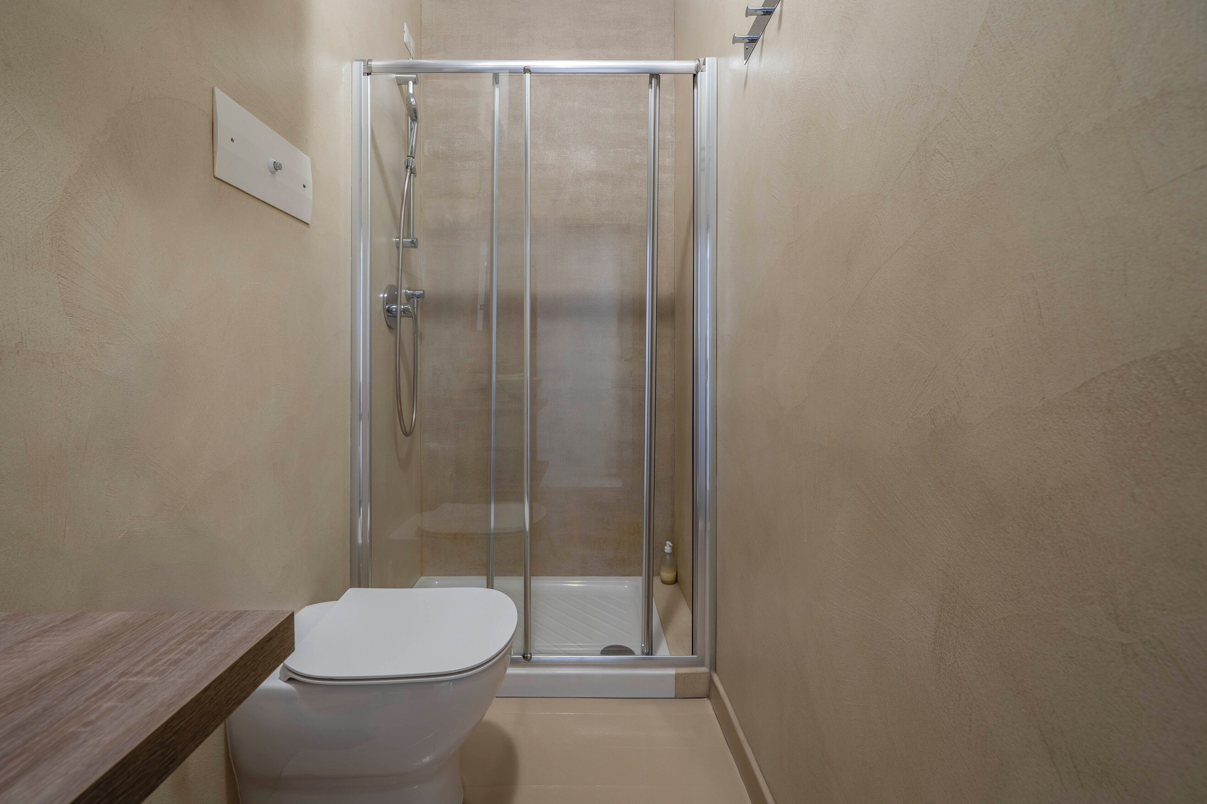 Een badkamer met een douchecabine van glas, een toilet en een houten wastafelmeubel.