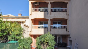 A multi-story building with balconies, a door with a glass panel, and a small outdoor seating area.