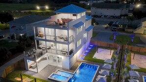 Uma casa moderna de dois andares com uma varanda grande, piscina e área de estar externa.