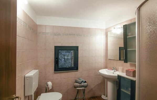 A bathroom with a toilet, sink, and mirror.
