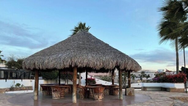 A thatched-roof gazebo with outdoor seating, surrounded by stone steps and palm trees. - Villa Serena 2

 (San Carlos)