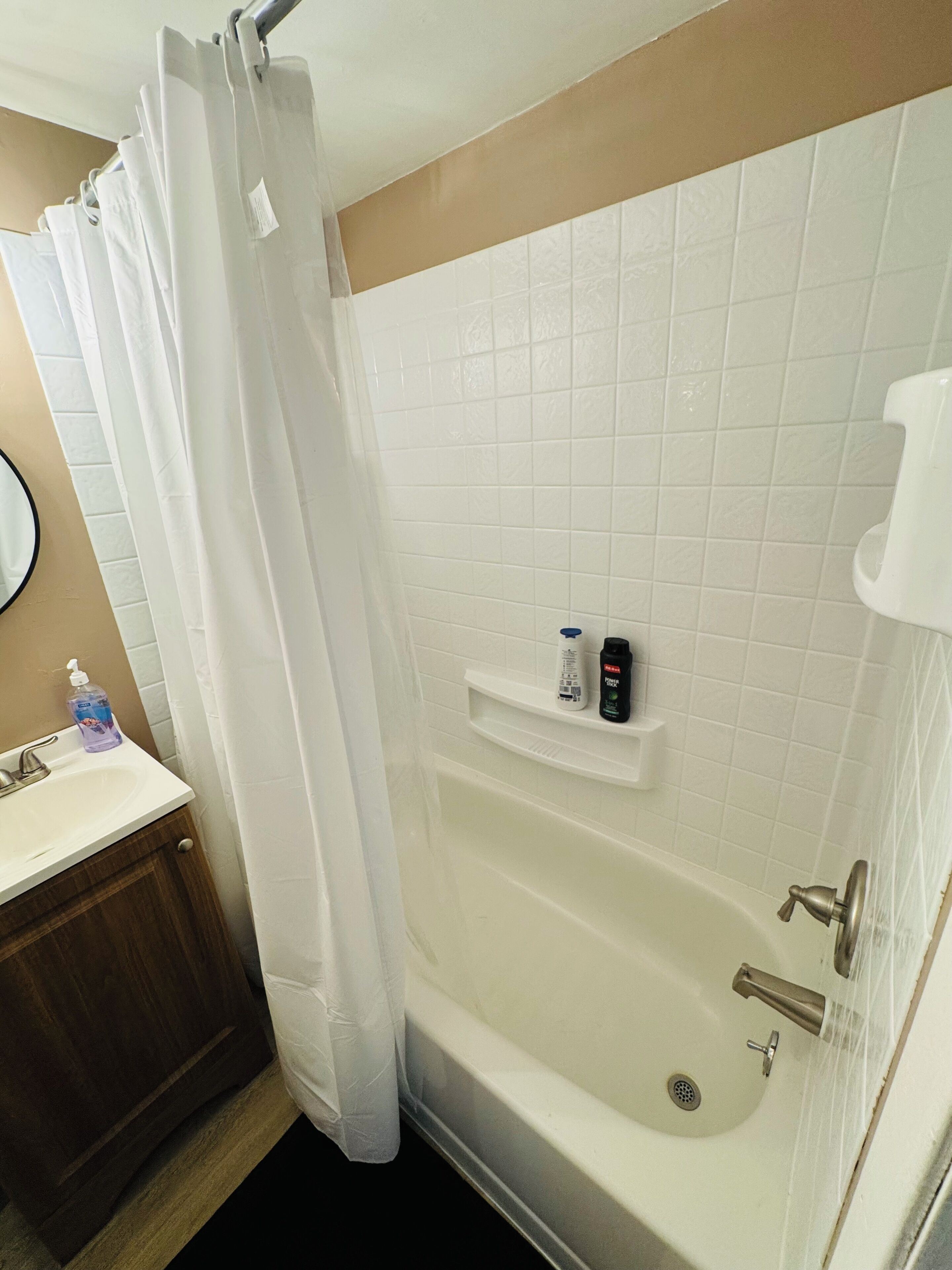 Une salle de bain avec une baignoire, un lavabo, un miroir et une étagère contenant des articles de toilette.