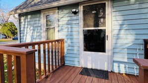 A house with a wooden deck, a front door, and a window. - Super Modern 2-Bedroom Riverside Home @ RIT (Rochester)