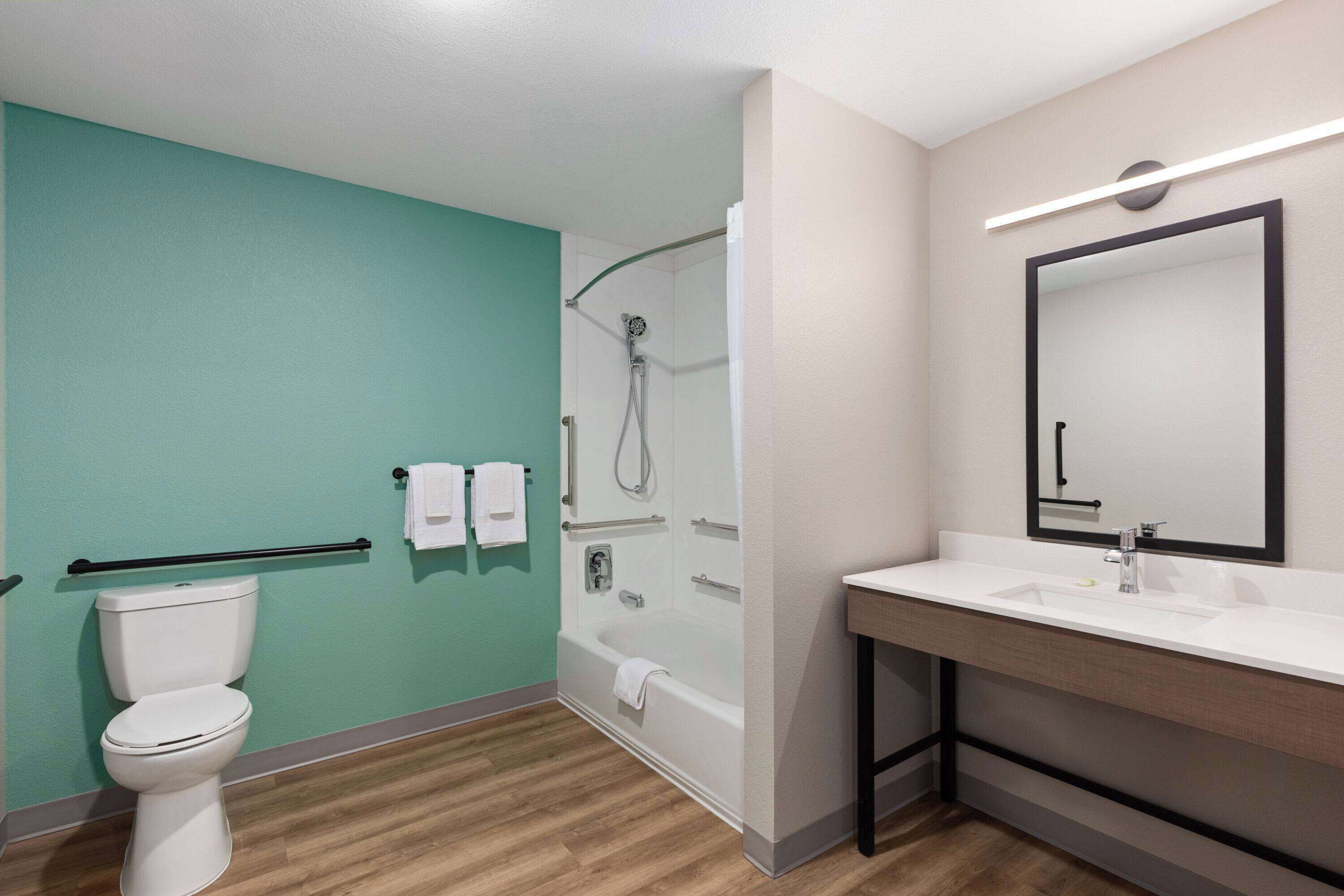 Un baño moderno con inodoro, ducha y lavabo con espejo.