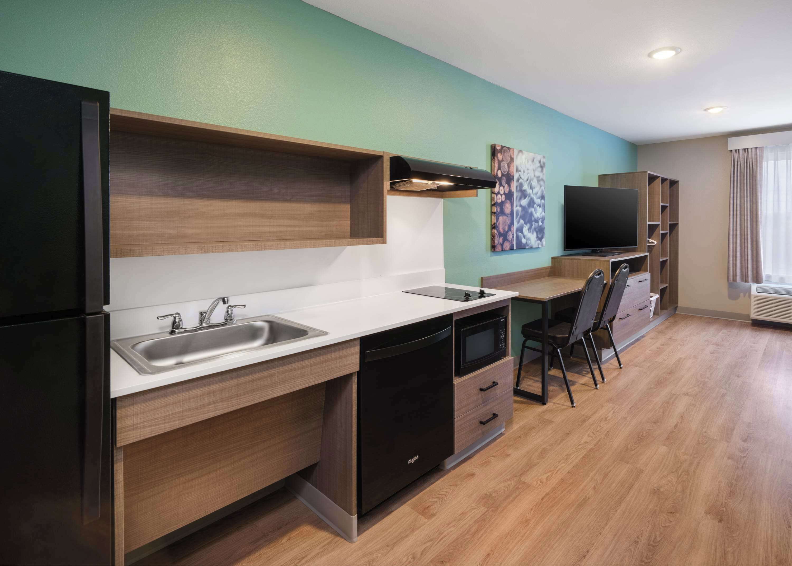 Una cocina compacta con lavamanos, microondas y un comedor con una silla y mesa.
