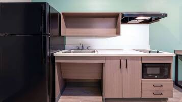 A compact kitchen with a black refrigerator, a microwave, and a sink.