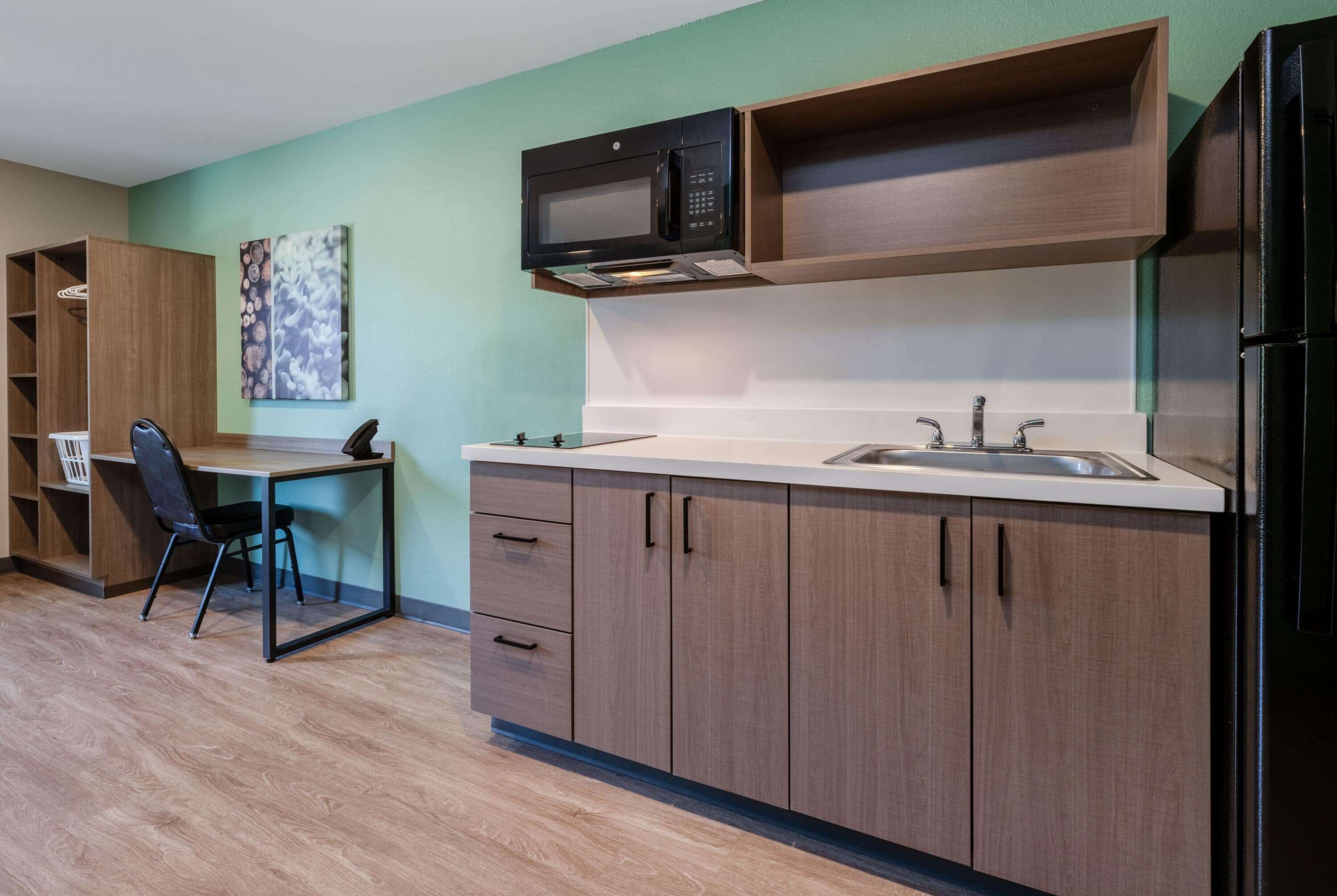 A modern kitchen with wooden cabinets, a microwave, a sink, and a refrigerator.