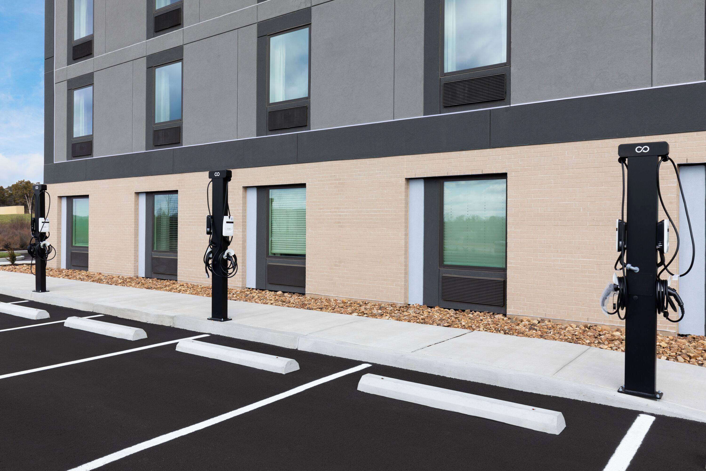 A modern building with a parking area and electric vehicle charging stations.