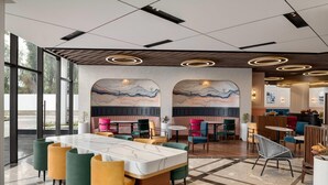 A modern restaurant with a marble table, colorful chairs, and a mural on the wall. - Ramada Encore By Wyndham Rajbagh Srinagar (Srinagar)