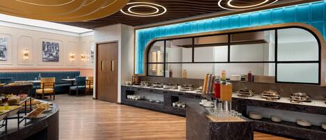 A modern restaurant with a curved counter, wooden flooring, and a blue accent wall.