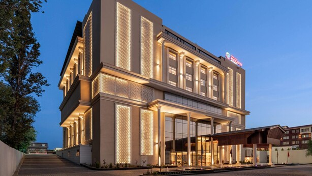 A modern hotel with a large entrance, a covered outdoor area, and a sign indicating it is a Marriott hotel. - Ramada Encore By Wyndham Rajbagh Srinagar (Srinagar)