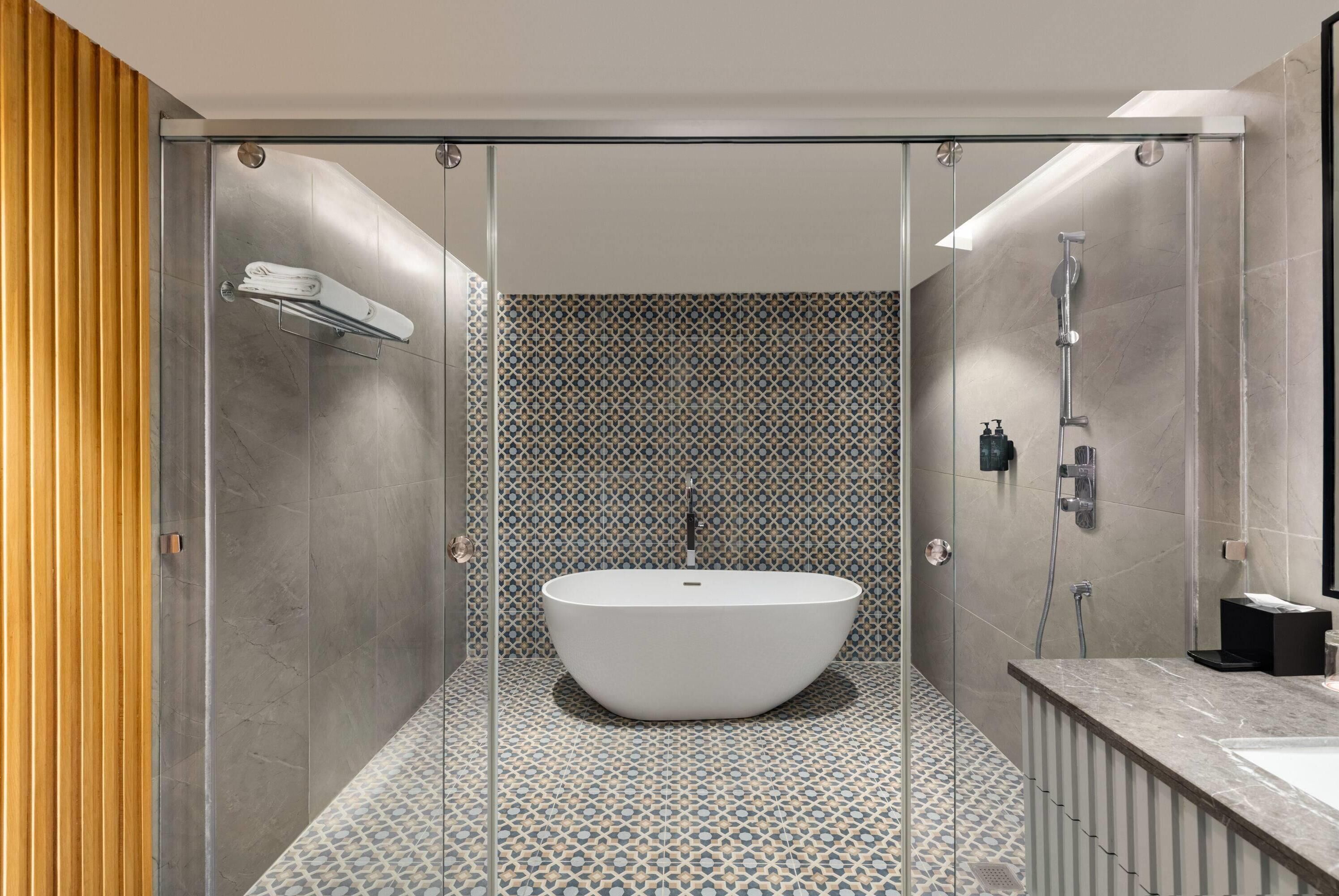 A modern bathroom with a freestanding bathtub, a glass shower enclosure, and a tiled floor.