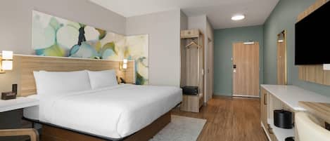 A modern hotel room with a large bed, bedside tables, a TV, a wardrobe, and a bathroom.