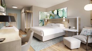 A modern hotel room with a large bed, a desk, a chair, and a small ottoman. - Wyndham Garden Tampa Fairgrounds/Casino (Tampa)