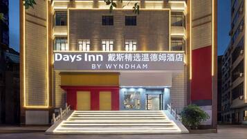 A hotel entrance with a sign for Days Inn by Wyndham, featuring a modern design with illuminated steps and a red and yellow facade.