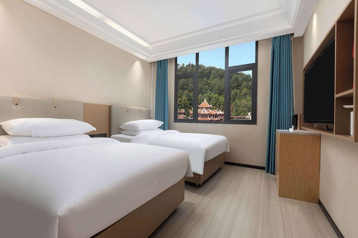 Une chambre d’hôtel avec deux lits, une télévision et une fenêtre donnant sur un bâtiment traditionnel.