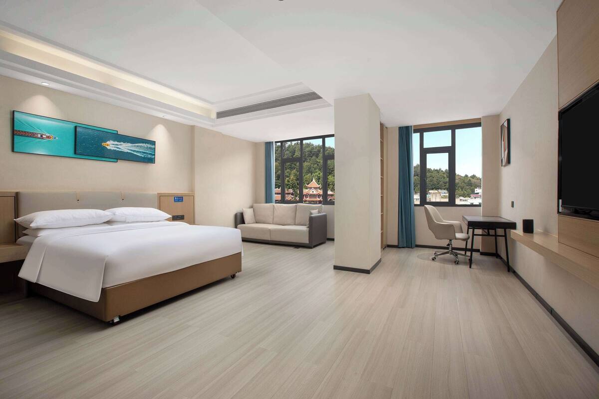 Une chambre d’hôtel moderne équipée d’un lit, d’un canapé, d’un bureau et d’une télévision.