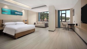 Una habitación de hotel moderna con cama, sofá, escritorio y televisor.