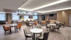 Un moderno vestíbulo de hotel con varias zonas de estar, un bar central y una recepción.