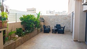 A patio area with a stone wall, potted plants, and outdoor furniture.
