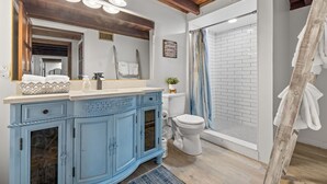 Ein Badezimmer mit blauem Waschtisch, weißer Toilette und einer Dusche mit blauer Duschvorhang.