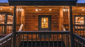 A wooden cabin with a porch, a door with a window, and a staircase leading up.