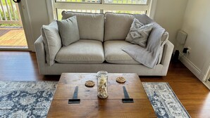 Un salon avec un canapé beige, une table basse en bois agrémentée d’objets décoratifs et un tapis à motifs.