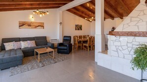 Ein Wohnzimmer mit grauem Sofa, einem Holztisch und einem Essbereich mit Kamin aus Stein.