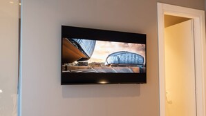 A flat-screen TV mounted on a wall displaying a modern building. - Your room like in a 4-star Hotel (Roma)